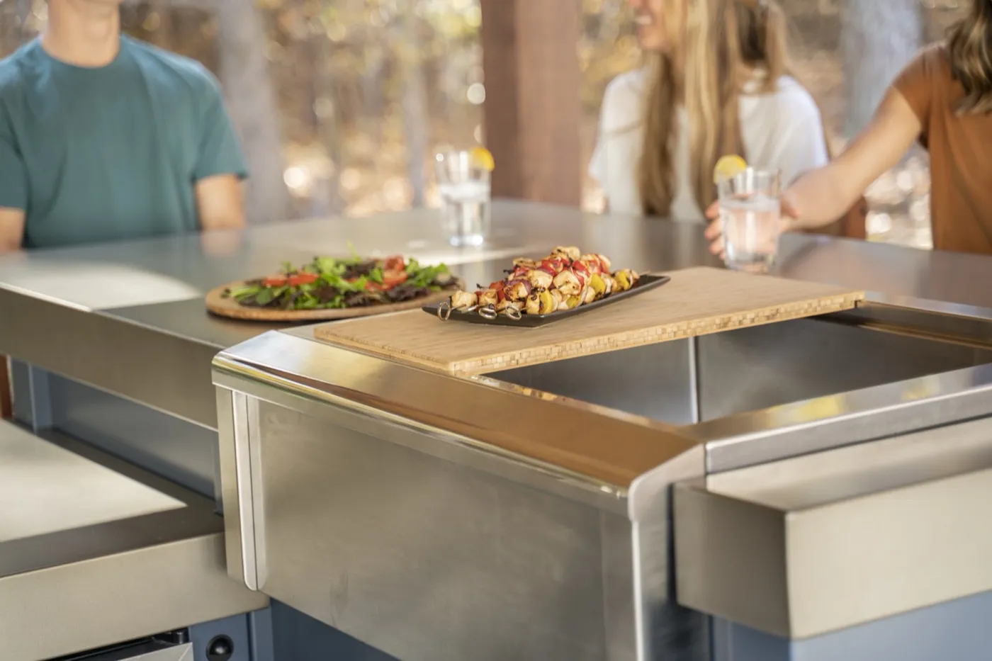 Skewers and salad served on the bamboo board of a stainless Stoll outdoor kitchen island