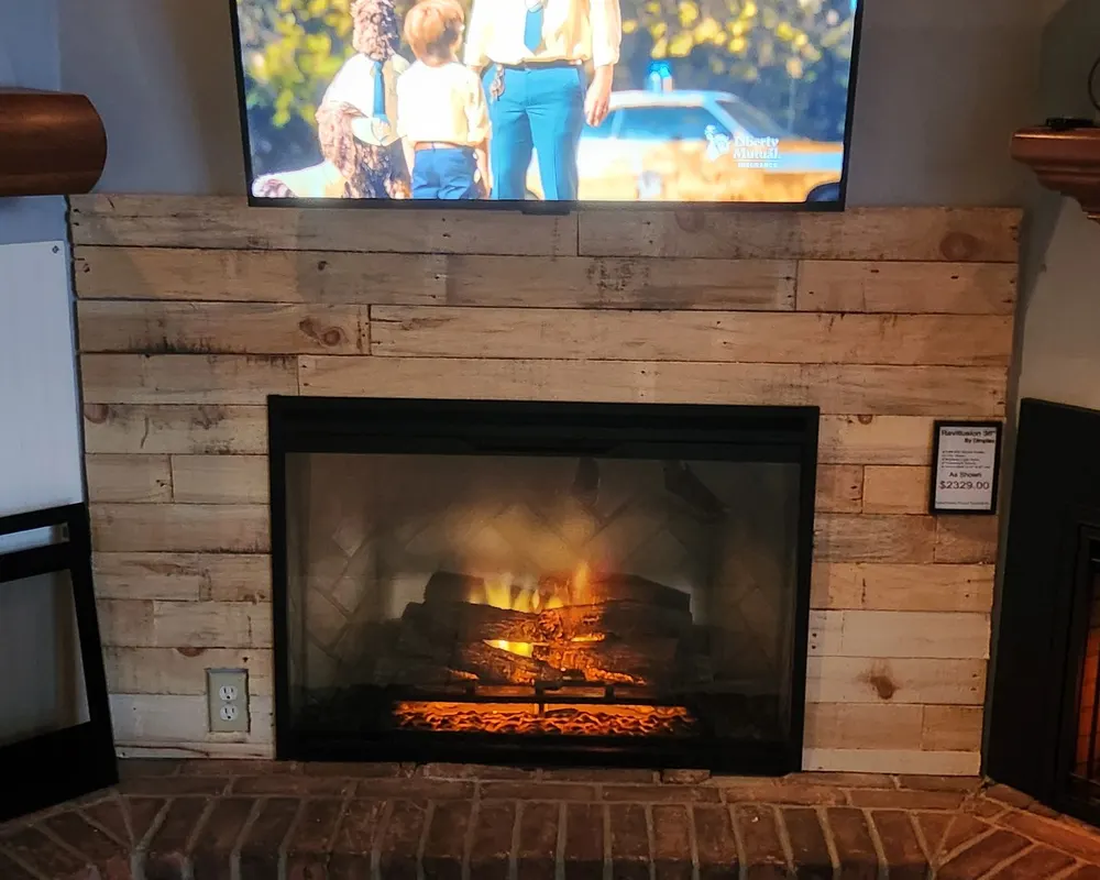 A wide gas insert burning under a shiplap accent wall