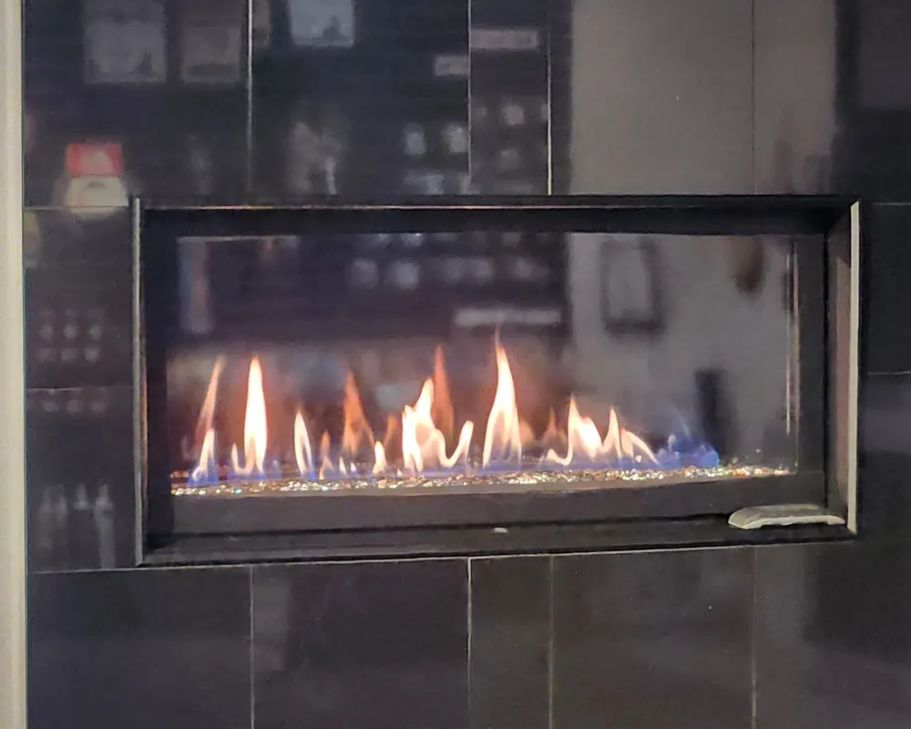 A linear gas fireplace burning in dark tile