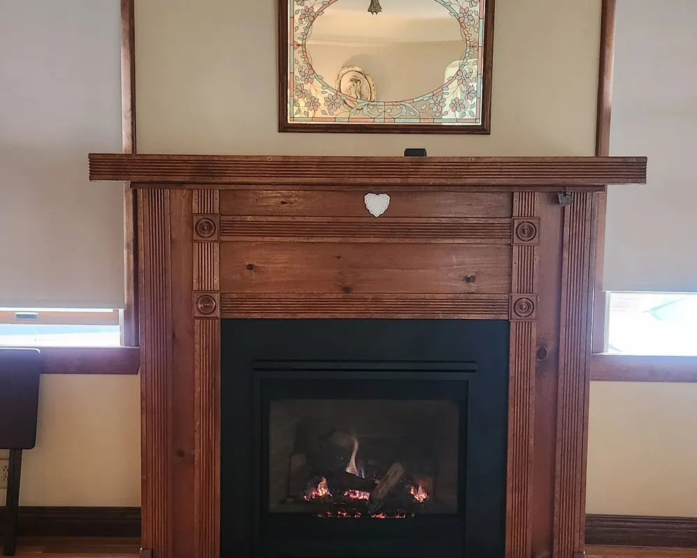A lit insert under a wooden mantel and mirror